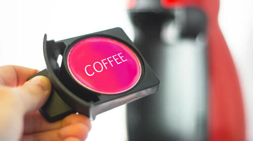 A coffee capsule and a coffee machine in the background