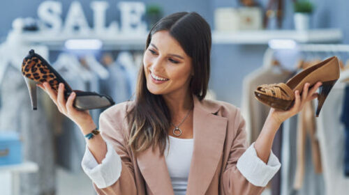 Young nice girl in store during shopping holding shoes. High quality photo